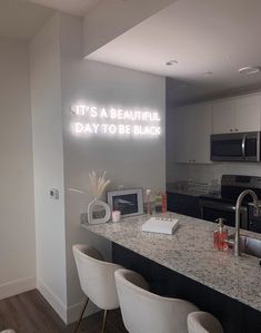 a kitchen with white chairs and an illuminated sign on the wall that says it's a beautiful day to be black