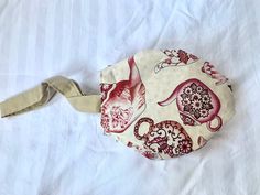 a white and red bag on top of a bed covered in sheets with an animal design