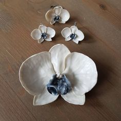 three white and blue flowers sitting on top of a wooden table next to each other