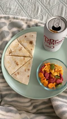 a can of soda and some food on a plate next to a bowl of gummy bears