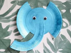 an elephant made out of paper plate sitting on top of a wall