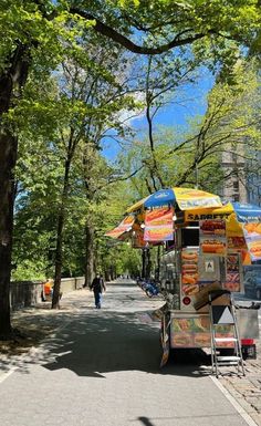 a food cart is parked on the side of the road in front of some trees