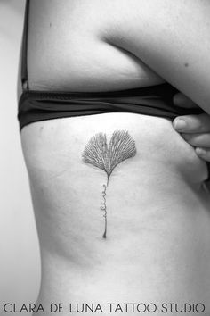 a woman's stomach with a small tattoo on the side of her belly and a flower