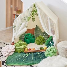 an indoor play tent with plants and food in the middle, on top of a rug