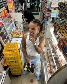 a woman with dreadlocks standing in front of a store counter talking on her cell phone