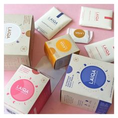 several boxes of soap sitting on top of a pink table cloth covered in white and yellow labels