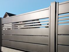 a metal fence with horizontal slats on the top and bottom, in front of a house