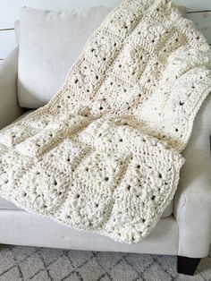 a white crocheted blanket sitting on top of a couch