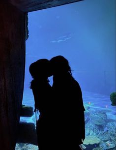 two people are kissing in front of an aquarium