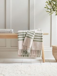 a white and green towel sitting on top of a wooden bench next to a potted plant