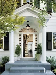 a white house with black shutters on the front door and windows in the entry way