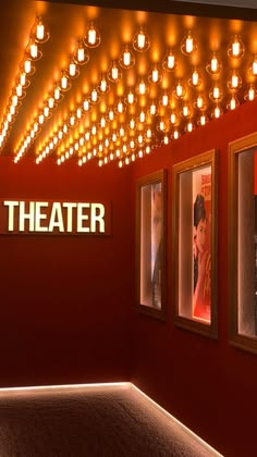 the theater sign is lit up in front of three framed movie posters on a red wall