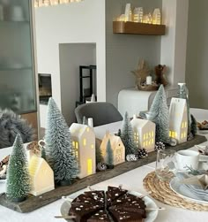 a dining room table set for christmas with plates, cups and cakes on the table