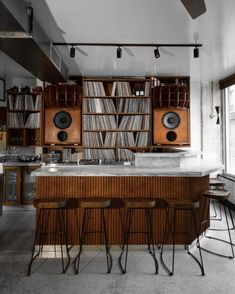 an old record player is on the wall in this room with wooden cabinets and bar stools