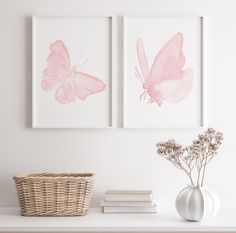 two pink butterflies are on the wall above a white shelf with books and vases