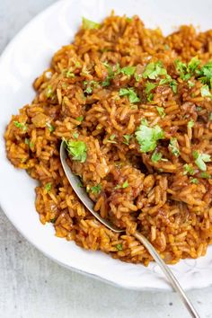 a white plate topped with mexican rice and garnished with cilantro leaves