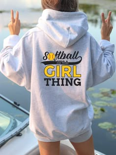 a woman standing on top of a boat wearing a hoodie that says softball is a girl thing