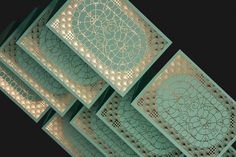 four cards with intricate designs on them in green and gold foiled paper, set against a black background