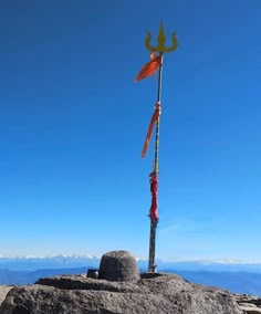 a flag on top of a rock with mountains in the background