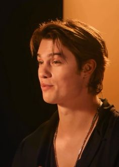 a young man wearing a black shirt and necklace