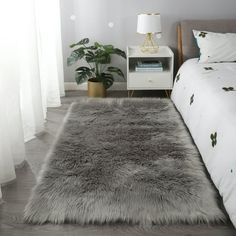 a bedroom with a bed, nightstand and rug on the floor in front of it