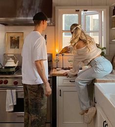 a man and woman standing in a kitchen preparing food on a counter top next to an oven