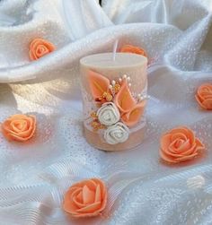 there is a candle that has been decorated with flowers on the table and white fabric