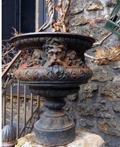 an old iron planter sitting on top of a stone slab next to a fire hydrant