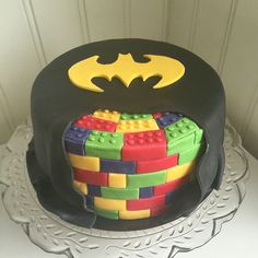 a birthday cake decorated with lego blocks and a batman logo on top, sitting on a table