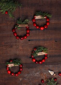 an image of christmas wreaths with red berries and pine needles on wooden planks