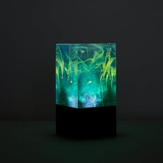 a green and black vase sitting on top of a dark surface with lots of light coming from it