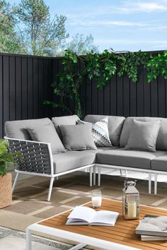 a couch and table on a patio with plants in the backgroung area