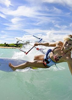 a woman on a surfboard in the water with her legs spread out and holding onto two skis