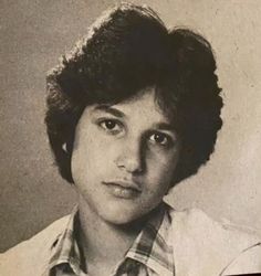 an old black and white photo of a young man with short hair wearing a plaid shirt