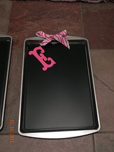 two black trays with pink monogrammed letters and a bow on the side