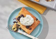 a piece of cake on a blue plate with whipped cream and fork next to it