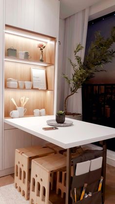 a white table and some shelves with plants on it in a room that has wood flooring