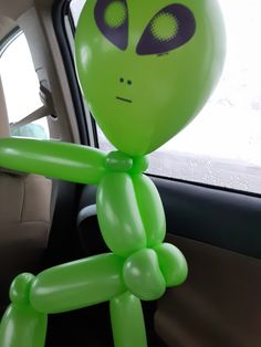 an inflatable green alien sitting in the back seat of a car