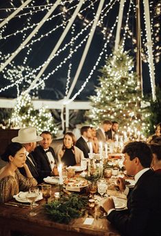 a group of people sitting at a table with food and candles in front of them