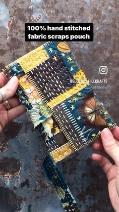 two hands are holding a piece of fabric that has been stitched together with butterflies on it