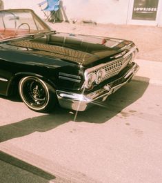 an old black car is parked on the street