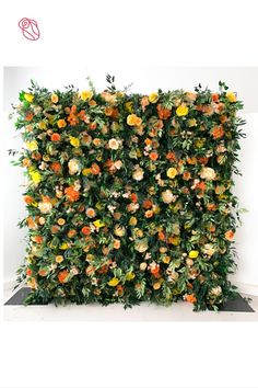 an artificial plant wall with orange and yellow flowers on it's sides, in front of a white background