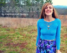 a woman standing in a field wearing a blue sweater and floral skirt with the words magnetic written above her