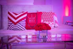 pillows on a couch with red flowers in the foreground and pink lighting behind them