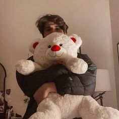 a man is holding a large white teddy bear in his arms while wearing a black puffy jacket