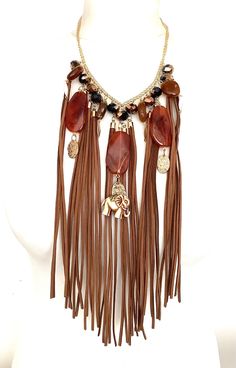 Tan suede tassel and bead statement necklace from Olivia Divine. Long tan suede tassels, beads and elephant charm necklace. Set on a gold tone chain. Adjustable length. Perfect for festivals. Chic Brown Dangle Jewelry, Party Tassel Dangle Necklaces, Party Dangle Necklaces With Tassels, Party Necklaces With Tassels And Dangle Shape, Brown Tassel Necklace For Festival, Gold Tassel Necklaces For Festival, Brown Bohemian Tassel Necklace, Brown Tassel Jewelry For Festivals, Bohemian Brown Tassel Jewelry