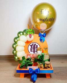 an orange box with balloons and confetti in it sitting on a wooden table