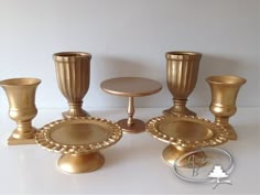 a group of golden candlesticks sitting on top of a white table next to each other