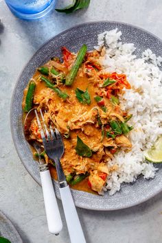 a plate with rice, green beans and chicken on it next to a glass of water