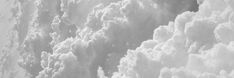 black and white photograph of clouds in the sky from an airplane window looking down at it